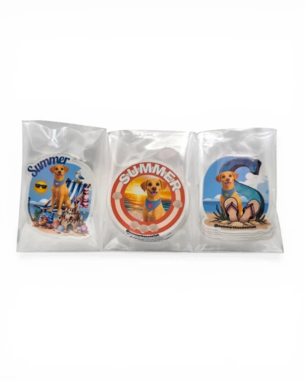 Three custom pet stickers of a yellow Labrador in beach scenes, packaged in clear poly bags. Windy City Tailz custom pet sticker order photo.